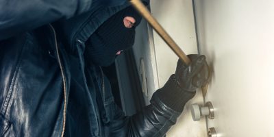 Ladrón intentando entrar en una casa con una palanca en la puerta