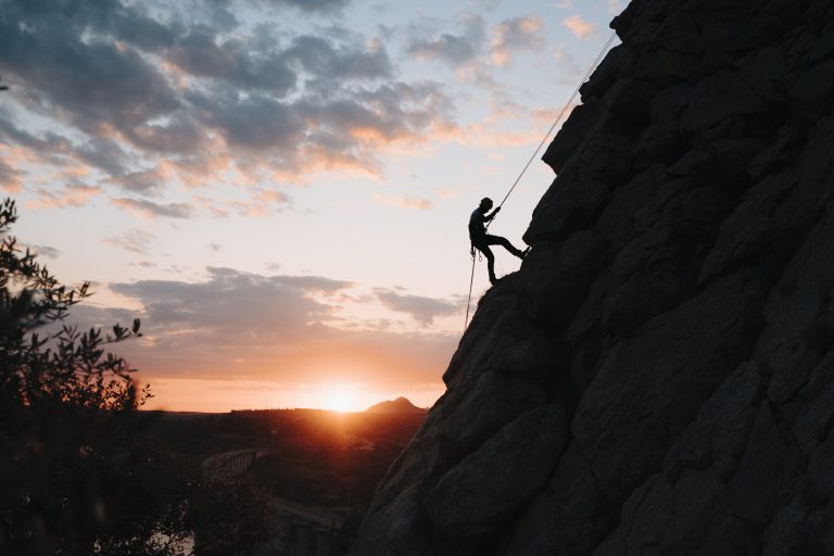 Hombre al atardecer haciendo una vía ferrata
