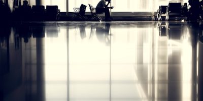 Fotografía en blanco y negro de un hombre sentado en un aeropuerto esperando para viajar.