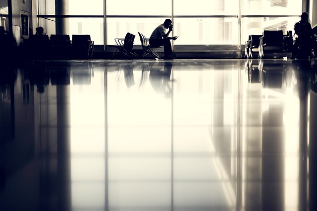 Fotografía en blanco y negro de un hombre sentado en un aeropuerto esperando para viajar.