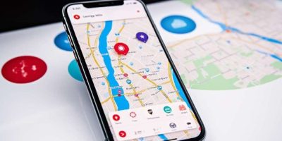 Teléfono móvil encima de un mapa con un app de viajes abierta en pantalla