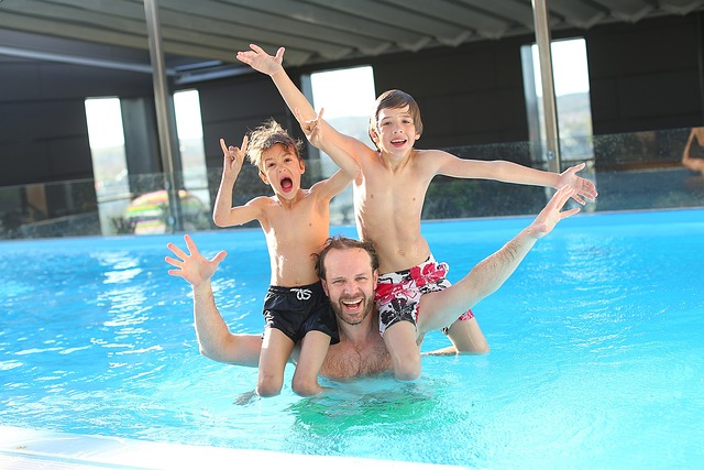 hombre con dos niños bañándose en piscina
