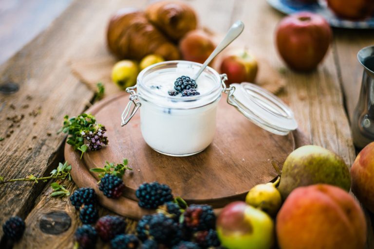 Tarro de yogurt griego muy bien presentado con frutas alrededor