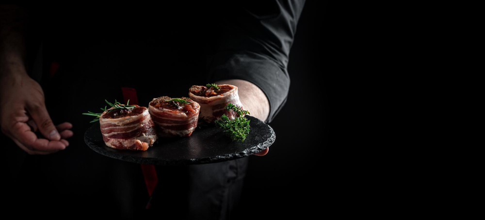 Chef de cocina con plato de barro con bistec en fondo negro