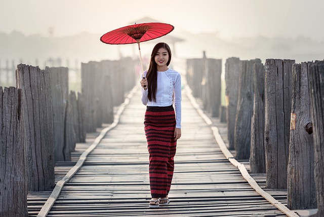 Una mujer está de pie en un puente de madera con una mochila y una sombrilla vietnamita
