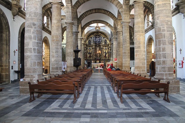 Una iglesia en Cádiz con bancos y arcos de madera.
