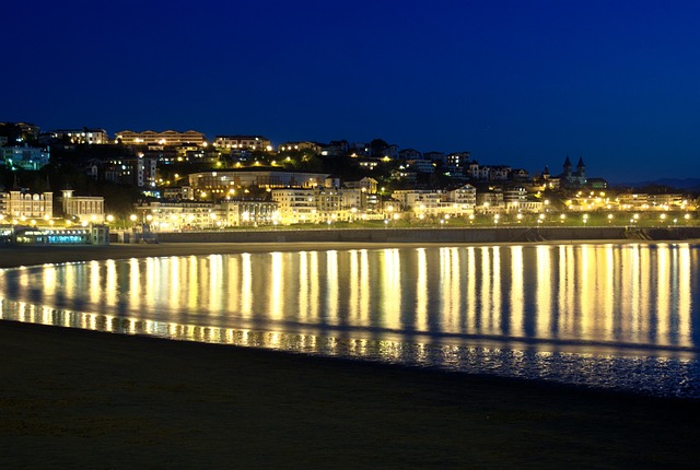 Qué ver en San Sebastián: Una ciudad de noche con una playa al fondo.