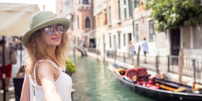Una mujer toma una mano mientras camina por un canal en Venecia, Italia.