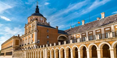 Una torre de reloj frente a un gran edificio. Palacio Real de Aranjuez