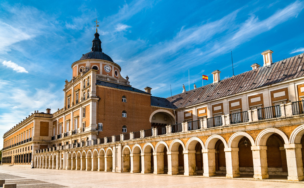 Una torre de reloj frente a un gran edificio. Palacio Real de Aranjuez