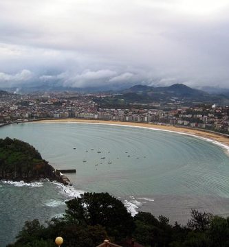 Una vista de una playa y montañas con un cielo nublado. San Sebastián