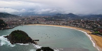 Una vista de una playa y montañas con un cielo nublado. San Sebastián