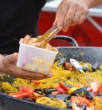 Un hombre cocinando una gran paella.