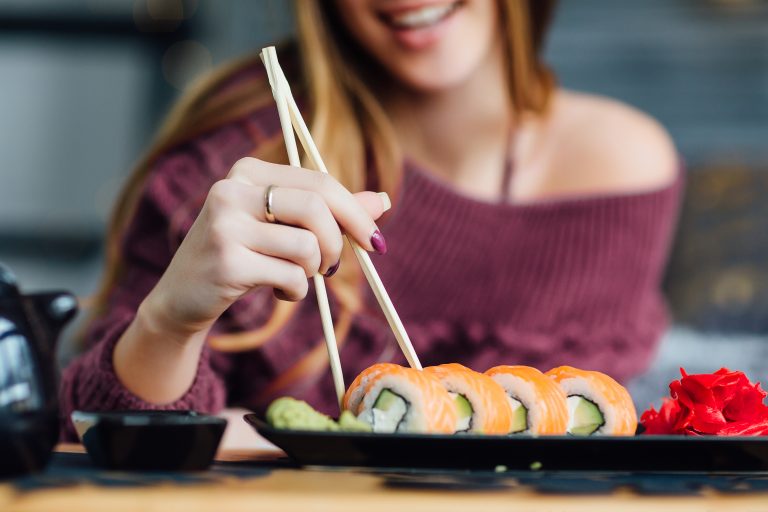 Una mujer disfruta de uno de los platos típicos de todo el mundo comiendo sushi con palillos.